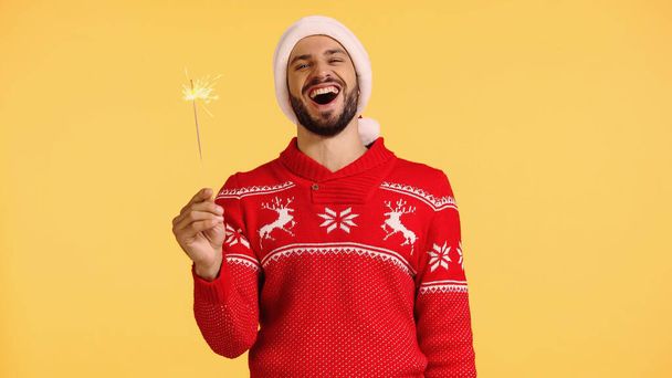 positive man holding shiny sparkler isolated on yellow - Foto, immagini