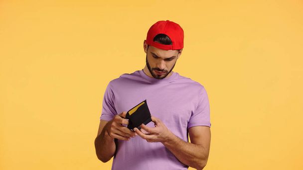 sad man looking at empty wallet isolated on yellow - Фото, изображение