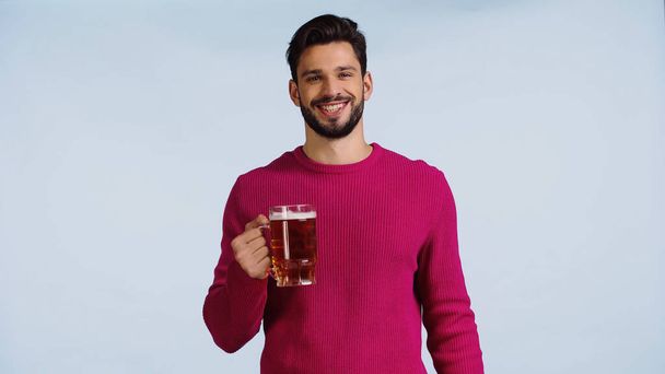 усміхнений чоловік тримає келих пива ізольовано на синьому
  - Фото, зображення