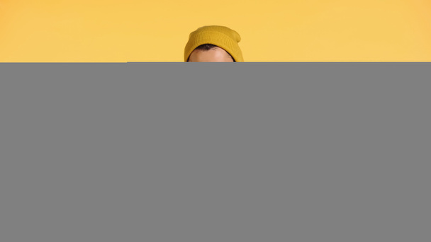 Şapkalı neşeli adam sarıda izole edilmiş akıllı telefondan konuşuyor. - Fotoğraf, Görsel
