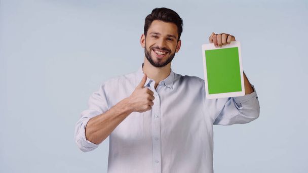 gelukkig man met duim omhoog en houden van digitale tablet met groen scherm geïsoleerd op blauw  - Foto, afbeelding