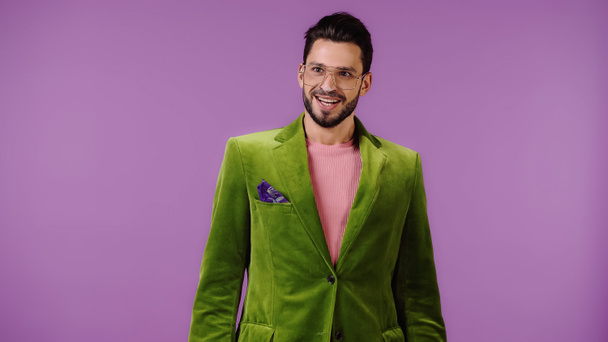 joven feliz en chaqueta verde aislado en púrpura - Foto, imagen