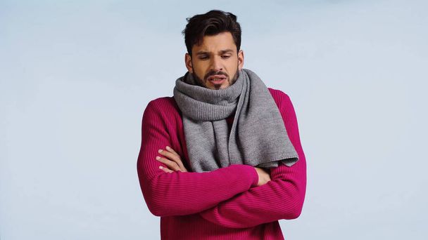 sick man in pink sweater and scarf standing with crossed arms isolated on blue  - Foto, Imagem