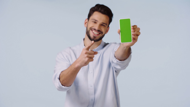 gelukkig man wijzen naar mobiele telefoon met groen scherm geïsoleerd op blauw  - Foto, afbeelding