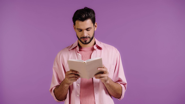 joven barbudo lectura libro aislado en púrpura - Foto, Imagen