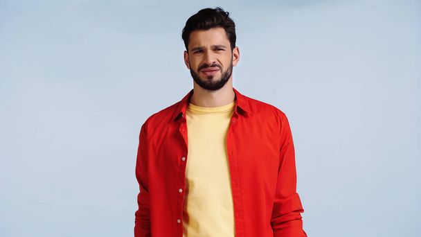displeased and bearded man in red shirt isolated on blue  - Φωτογραφία, εικόνα