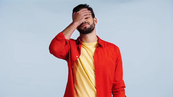 displeased and bearded man in red shirt doing face palm isolated on blue  - Foto, immagini