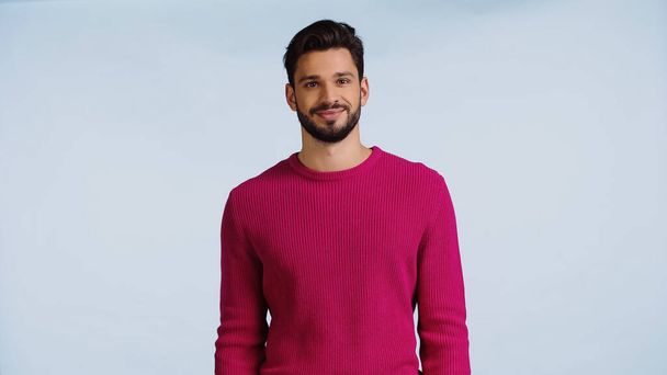 hombre alegre y barbudo en suéter rosa aislado en azul  - Foto, Imagen