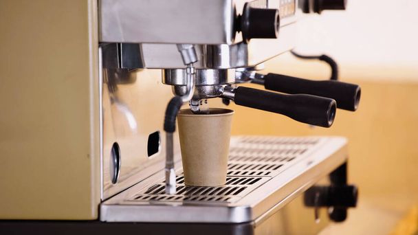 profesjonalny ekspres do kawy nalewający napój do papierowej filiżanki w nowoczesnej kawiarni  - Zdjęcie, obraz