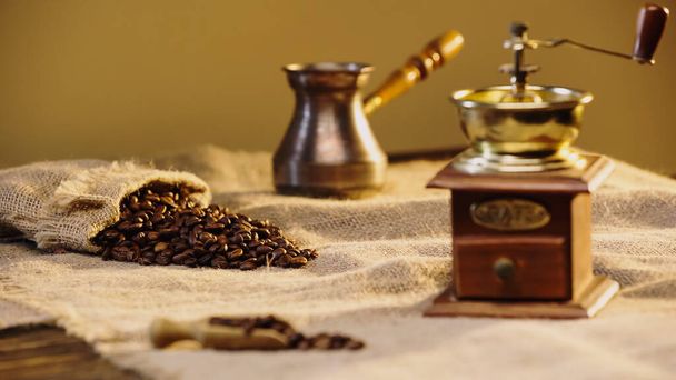 coffee beans in canvas bag near blurred coffee grinder  - Photo, Image