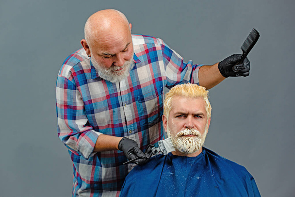 Hair coloring in gray color process. Hairdresser applying colorful tint on man models hair. Advertising and barber shop concept. Professional hairdresser drying hair in studio. - Fotó, kép