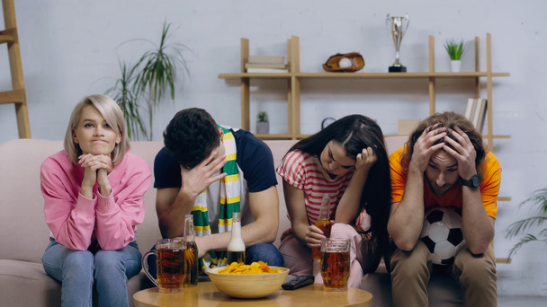 aficionados al fútbol frustrados sentados con la cabeza inclinada cerca de la cerveza y las patatas fritas en casa - Foto, Imagen