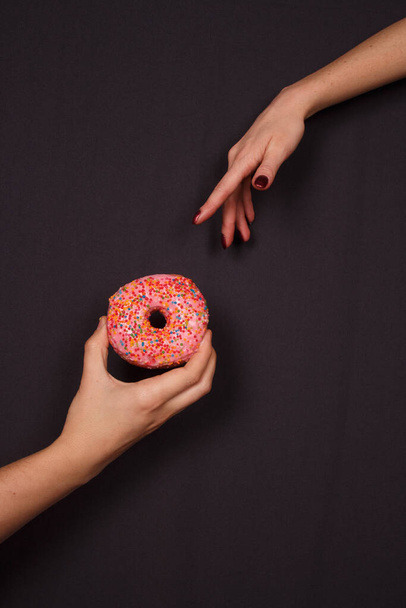 Typisch amerikanische Süßigkeiten - Donuts in der Hand auf dunklem Hintergrund - Foto, Bild