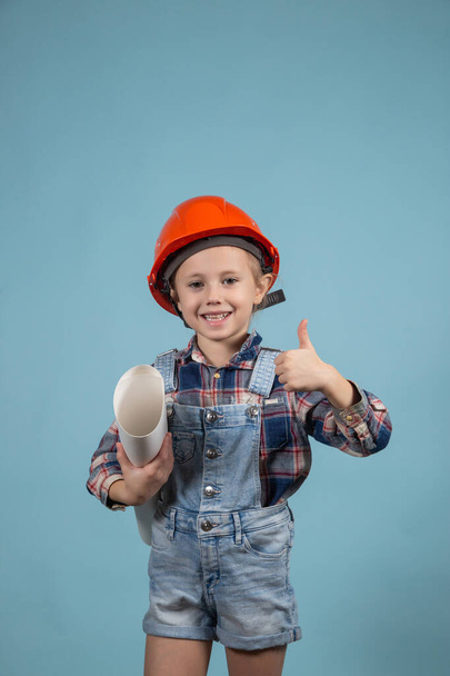 An adorable girl in an orange hard hat posing funny holding wrenches - Zdjęcie, obraz
