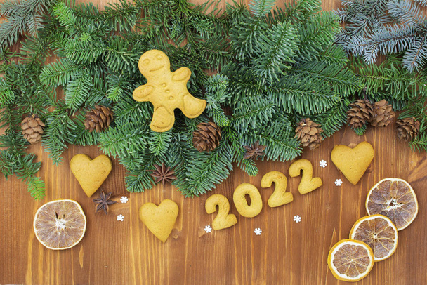 2022 numbers from the test. Christmas or New Year decoration background. Fir twigs, Christmas gingerbread cookies on a wooden vintage background. Top view of toys, spice cones. - Foto, Bild