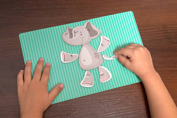 The child collects puzzles from the figure of an elephant. Early education, development. - Foto, imagen