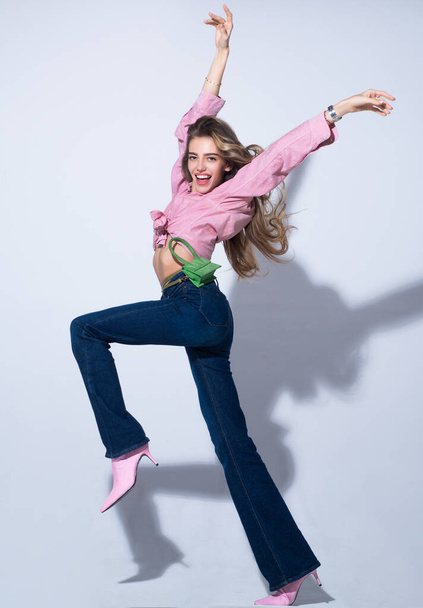 Movement model. Fashion woman in pink shirt and jeans. Young glamour woman wearing stylish fashion dress. Fashion model in studio, full length. - Fotó, kép