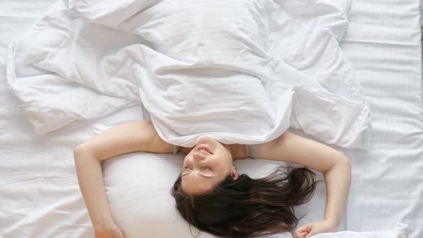 Mladá šťastná žena se probudí protahuje paže na posteli doma - Záběry, video