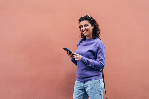 Cheerful ethnic woman with smartphone on street - Photo, image