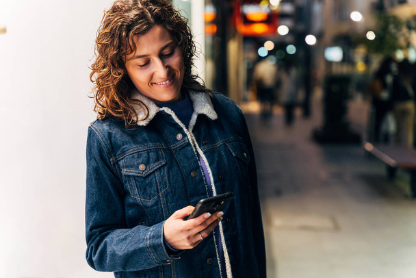 Young woman with smartphone on street - Foto, afbeelding