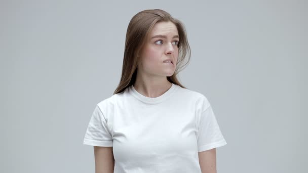 Ich weiß es nicht. Eine verlegene Frau mit langen, glatten Haaren im T-Shirt hebt fragend die Arme und blickt sich mit ratlosem Gesicht um - Filmmaterial, Video