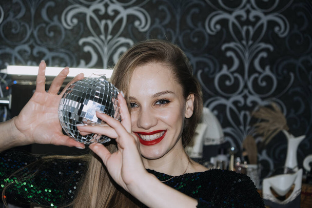 Nightlife, New year eve party, New year celebration. Portrait of young beautiful woman and disco ball - 写真・画像