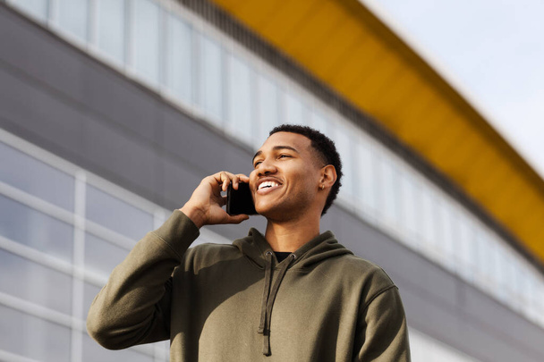 young african american man in casual outfit standing and talking on phone - Фото, зображення