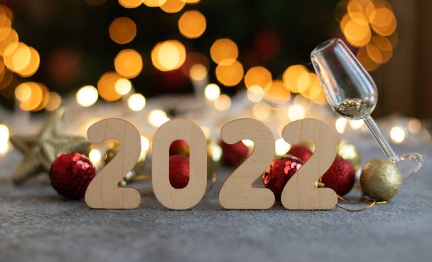Wooden numbers 2022, glass of champagne and defocus lights - Photo, Image