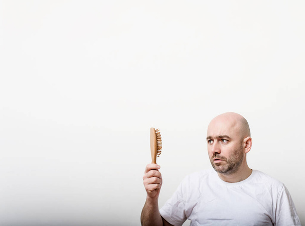 caucasian confused bald man trying hair brush. copyspace - Foto, Imagen