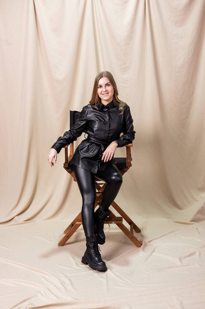 Stylish woman in black leather boots from the new fall-winter 2022 collection. Young woman dressed in a black leather shirt and leggings - Foto, Bild