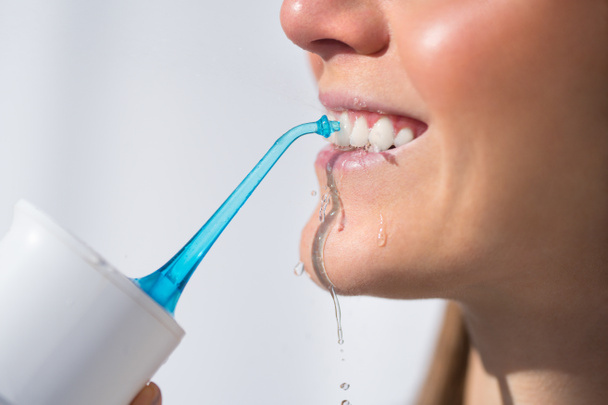 Mulher com sorriso branco perfeito usando fio dental de água portátil ou irrigador oral - Foto, Imagem
