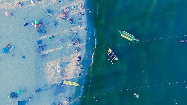 Playa de arena marina con gente descansando al amanecer en verano. Vista aérea. Vista de pájaro de la costa marina - Foto, imagen
