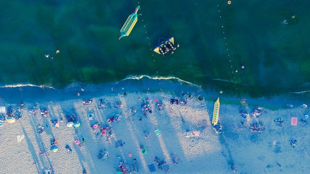 Playa de arena marina con gente descansando al amanecer en verano. Vista aérea. Vista de pájaro de la costa marina - Foto, Imagen