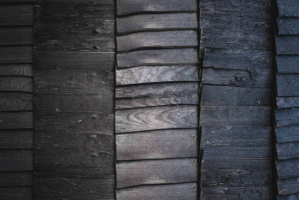 Black burnt wooden texture background. Beautiful, stylish boards pattern with optical illusion of movement and ombre effect. Igloo sauna or house exterior design. Harsh wood without finish. Copy space - Photo, Image