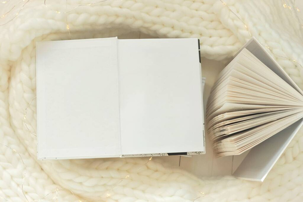 Winter books. Winter reading. Open white books with blank sheets with knitted scarf and garland.Cozy mood. Winter Season Christmas books. - Photo, Image