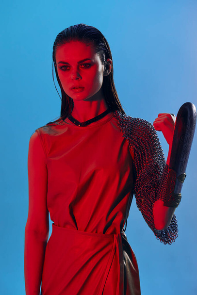 beautiful woman Glamor posing red light metal armor on hand blue background - Photo, Image
