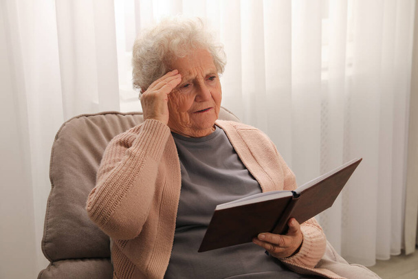 Senior woman with notebook at home. Age-related memory impairment - Fotoğraf, Görsel