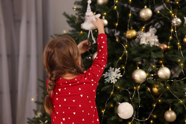 Cute little child decorating Christmas tree at home, back view - Φωτογραφία, εικόνα
