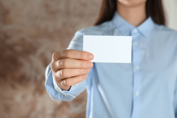 Woman holding blank business card on blurred background, closeup. Mockup for design - Foto, afbeelding