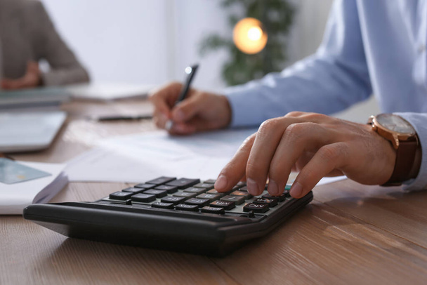 Tax accountant with calculator working at table in office, closeup - Photo, image