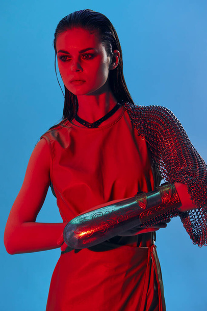 mooie vrouw rood licht zilveren armor ketting mail mode blauwe achtergrond - Foto, afbeelding