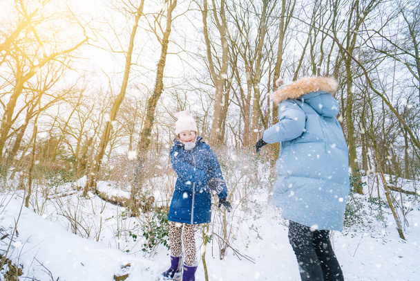 Kinder spielen im Winter auf Schnee. Glücklich lachende Kinder im schönen verschneiten Winterwald am Weihnachtstag. Glückliche Kindheit, aktives Winterurlaubskonzept. - Foto, Bild