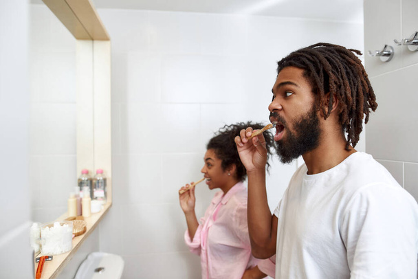 Couple brush teeth with toothbrushes in bathroom - Zdjęcie, obraz