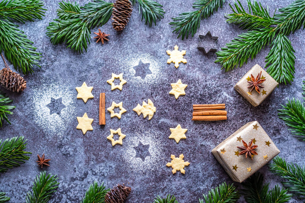 Christmas sweets and cookies in form of christmas tree placed on gray desk with pine cone and branch on the side. Winter and christmas decorations, cinnamon, sugar and star anise. - Foto, Imagem