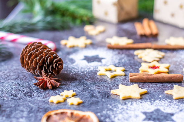 Christmas sweets and cookies placed on gray desk. Winter decorations, pine tree and cone. Concept of christmas, gifts and holidays. Glowing lights in the background. - Fotoğraf, Görsel
