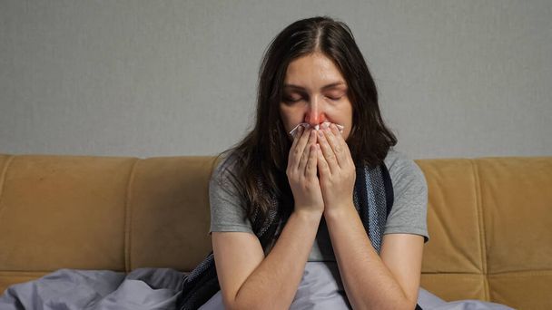 Mulher deprimida com corrimento nasal senta-se no sofá na sala de estar - Foto, Imagem