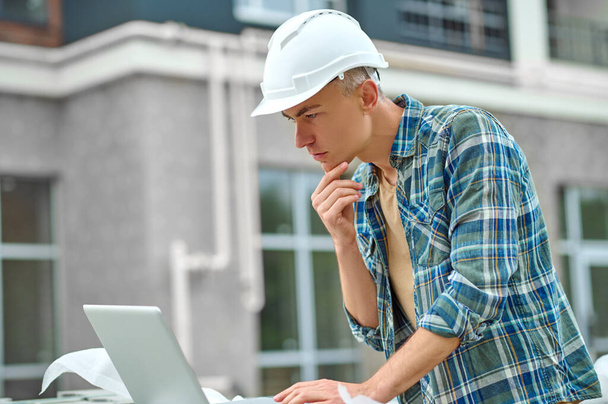 Profile of man looking into laptop at construction site - Foto, immagini