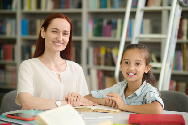 Woman and girl doing lessons looking at camera - Photo, image