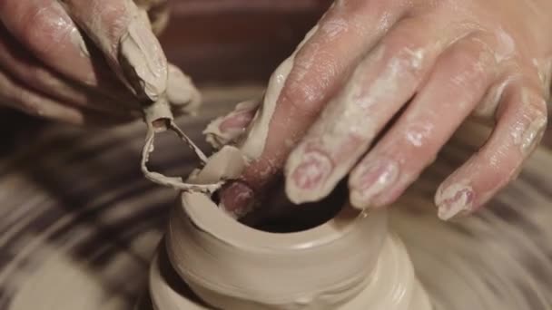 Taller de cerámica - manos femeninas mojadas moldeando la arcilla en el volante - cortando la parte superior usando un instrumento - Metraje, vídeo