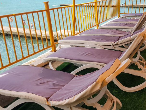 Puste leżaki z materacami na powietrznym aerarium do relaksu na plaży hotelu lub kurortu, na tle morza. - Zdjęcie, obraz